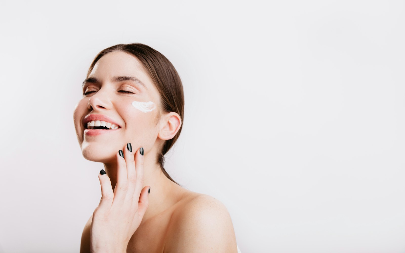 Smiling woman touching her face and neck as part of her skincare routine