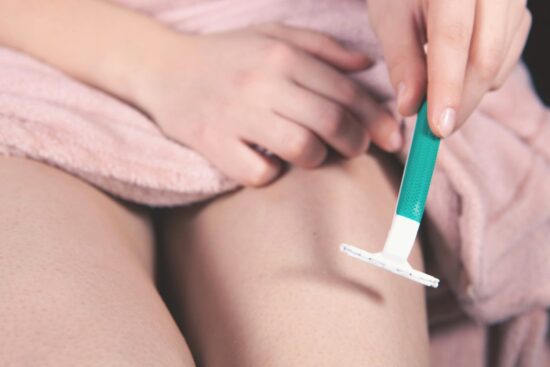 Woman shaving her leg with a razor, avoiding common shaving mistakes