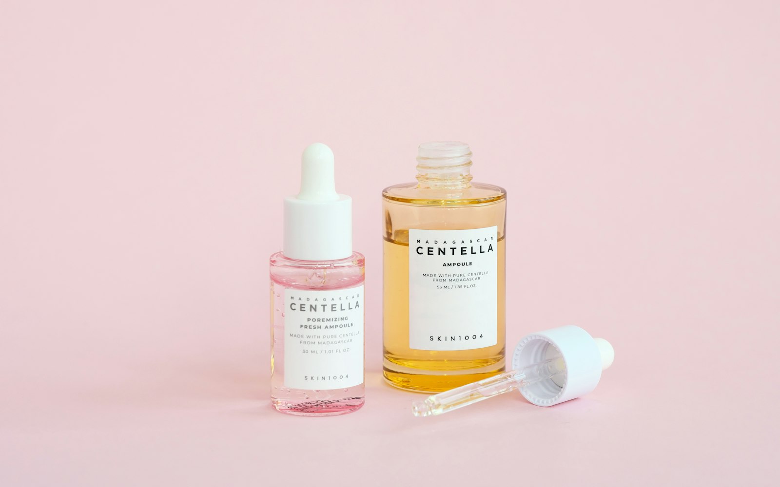 Skincare serums on a pink background