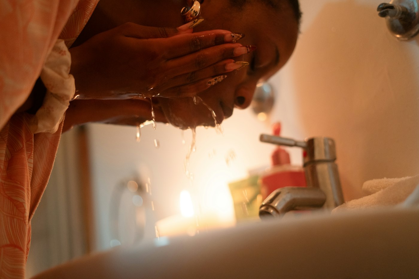 Woman washing her face and neck at the sink to help prevent neck wrinkles